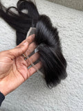 Black hair Toppers held in a hand against a textured gray background