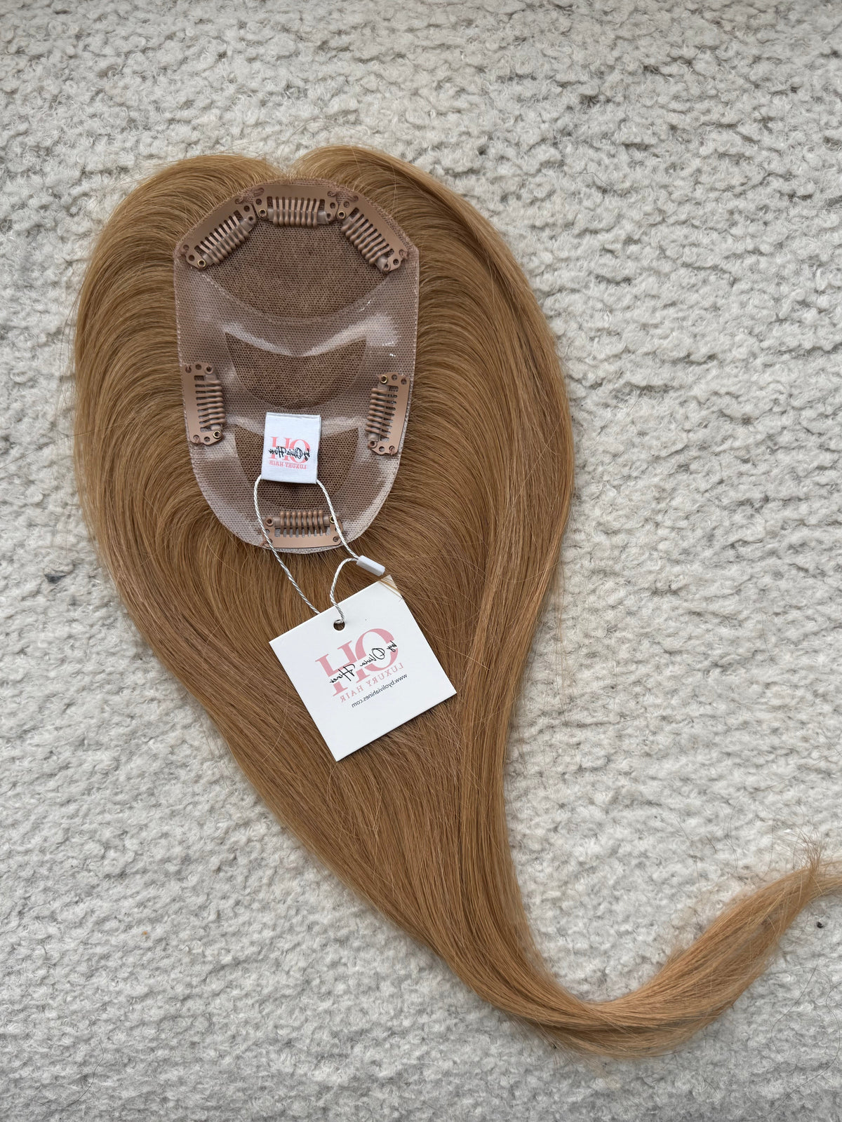 Brown hair Topper with a label on a textured surface