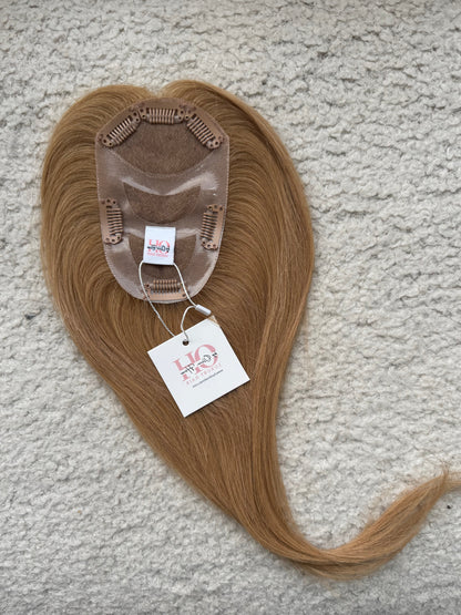 Brown hair Topper with a label on a textured surface